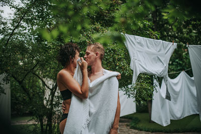 Couple with towel standing against trees