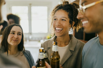 Happy young man and women standing with beer bottles in party