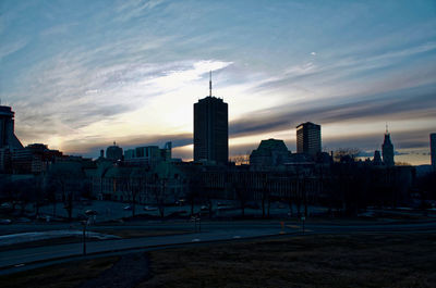 Modern buildings in city against sky during sunset