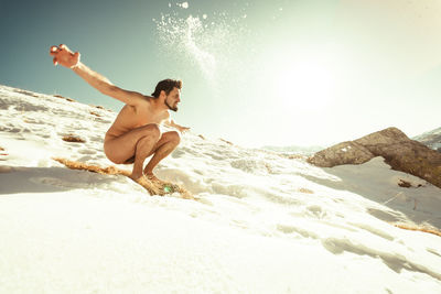 Full length of shirtless man at beach against sky