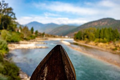 Close-up of river by mountains against sky
