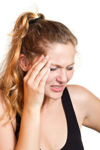 Close-up of young woman suffering from headache against white background