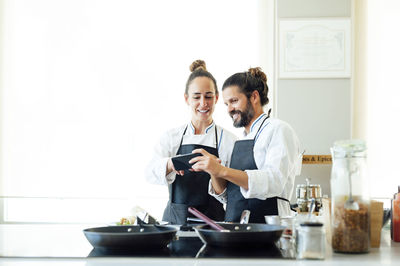 Young woman using smart phone while standing on laptop