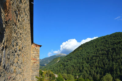 Low angle view of building and mountains against blue sky