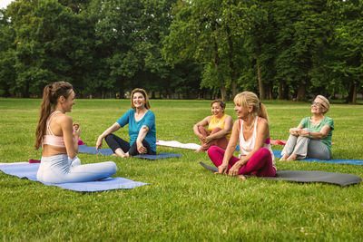 Happy friends sitting on grassy field