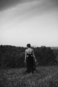 Rear view of woman standing on field against clear sky