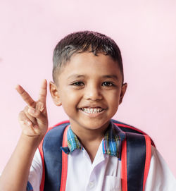 Portrait of smiling boy against pink background