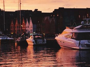 Sailboats moored at harbor against sky during sunset