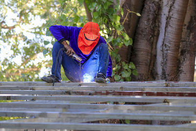 Man working on wood against trees