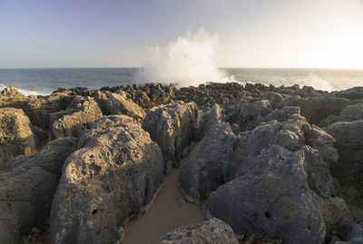 Scenic view of rocks on beach against clear sky