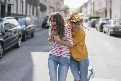 Two girlfriends having fun in the city, running