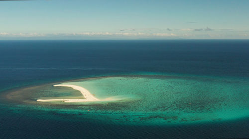 Beautiful beach on tropical island surrounded by coral reef, sandy bar with tourists, top view. 