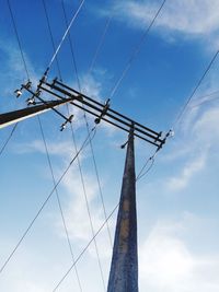 Low angle view of electricity pylon against blue sky