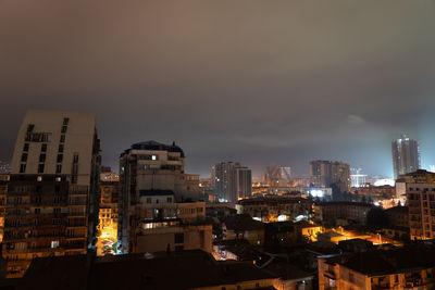 Illuminated buildings in city against sky at night