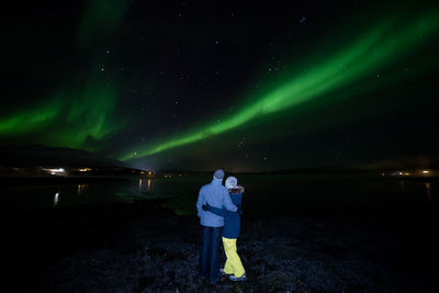 Rear view of a couple standing and watching aurora borealis