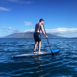 Full length of woman standing on sea against blue sky