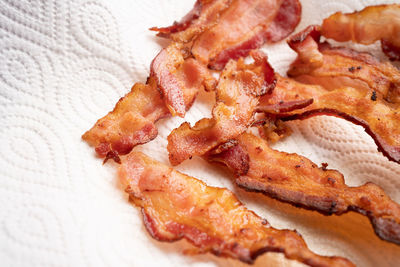 Close up top view of crispy bacon strips on oil-absorbing tissue paper in many shapes. keto food.