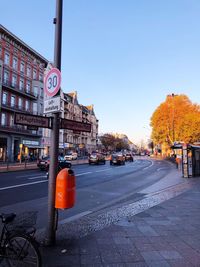 Road sign on street in city against clear sky