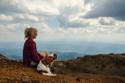 Woman and her dog, dressed in royal stewart, watching picturesque mountain landscape