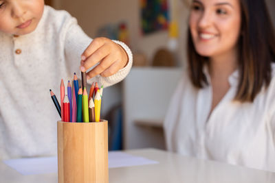 Smiling mother with son holding colored pencil at home