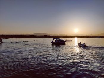 Silhouette boats in sea against clear sky during sunset