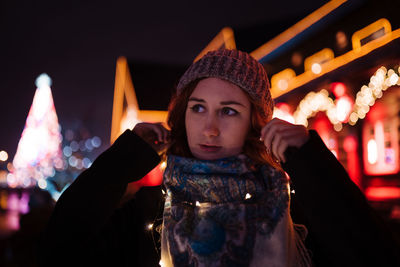 Portrait of young woman standing in illuminated traditional clothing