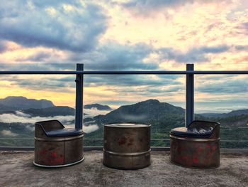 Metallic structure by mountains against sky during sunset