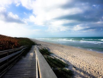View of empty beach against cloudy sky