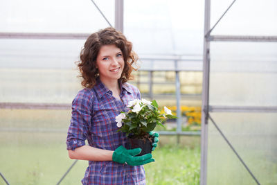 Portrait of smiling young woman standing in greenhouse