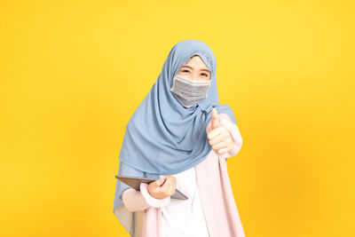 Portrait of mid adult man standing against yellow background