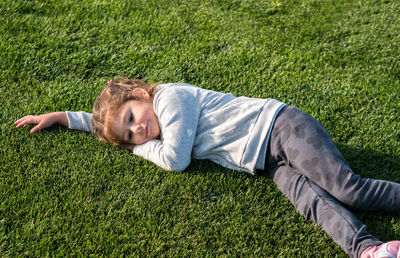 High angle view of girl lying on grassy field at park