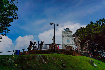 Low angle view of people by building against sky