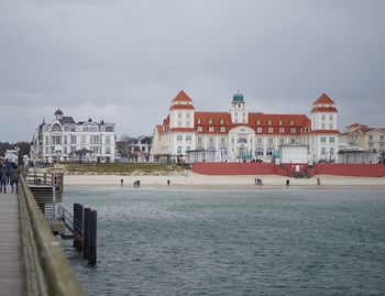 Buildings by sea against sky