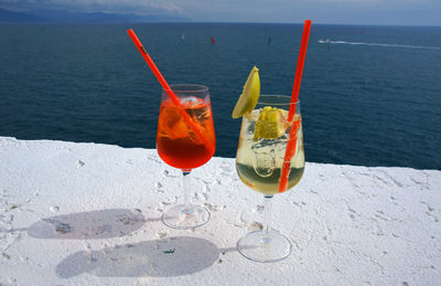 Drinks in glass on retaining wall against sea