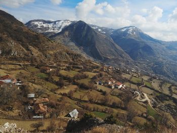 Aerial view of houses on field by mountains against sky