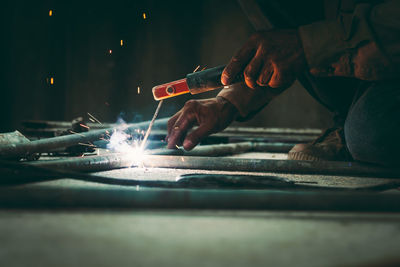 Cropped image of worker welding rods in factory