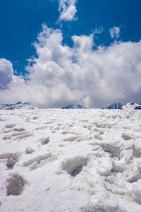 Snow covered land against blue sky