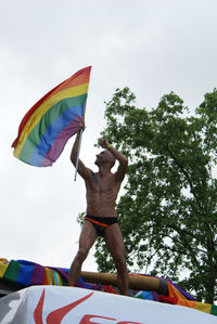 Low angle view of men on umbrella against sky