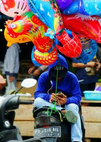 Rear view of man holding multi colored umbrella