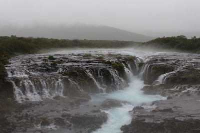 Scenic view of waterfall against sky