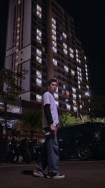 Full length portrait of young man standing in city at night