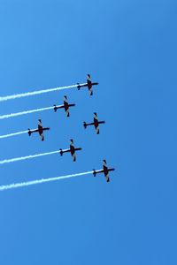 Low angle view of airplane flying against clear blue sky