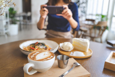 Midsection of woman photographing food using phone