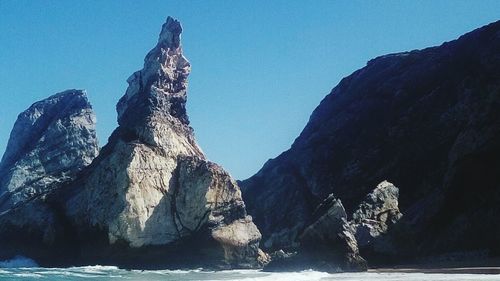 Scenic view of sea by mountain against sky