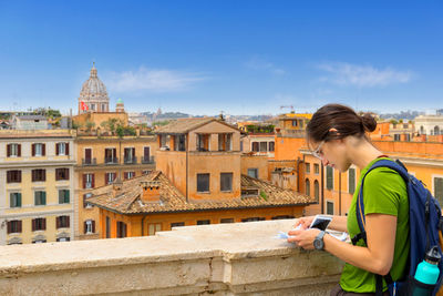 Young woman using mobile phone against buildings in city