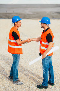 Engineers shaking hands over blueprint at construction site