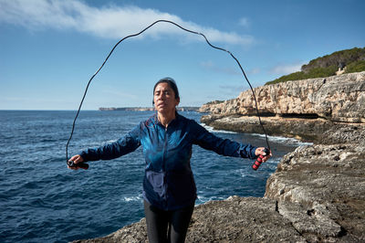 Woman skipping on rock against sea