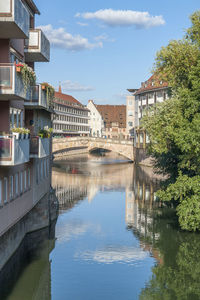 Arch bridge over river by buildings against sky