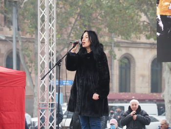 Young woman photographing with mobile phone standing outdoors