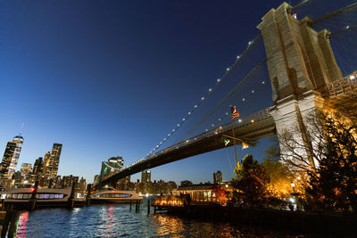 Illuminated bridge over river against sky at night